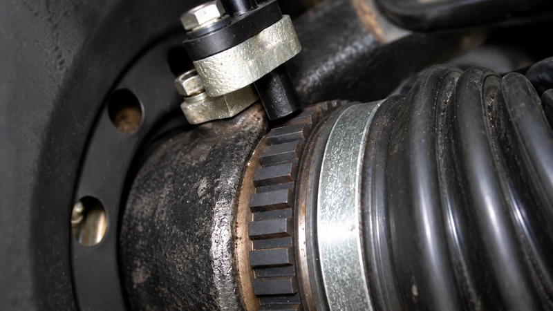 A wheel-speed sensor facing a toothed ABS ring across a small air gap, illustrating one indirect TPMS sensing arrangement