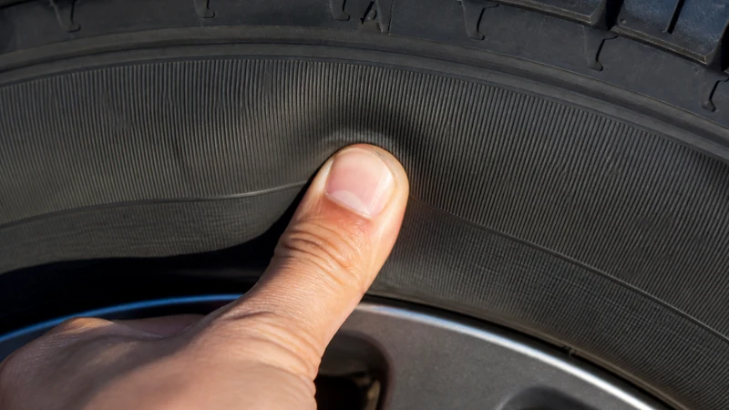 Thumb press test — pressing a thumb into the center of a tire sidewall to check firmness without a gauge
