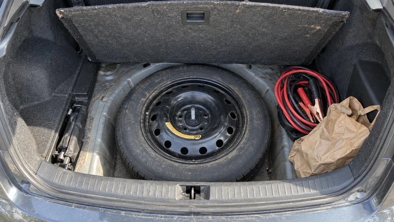 A compact spare tire in a car trunk, often forgotten for years